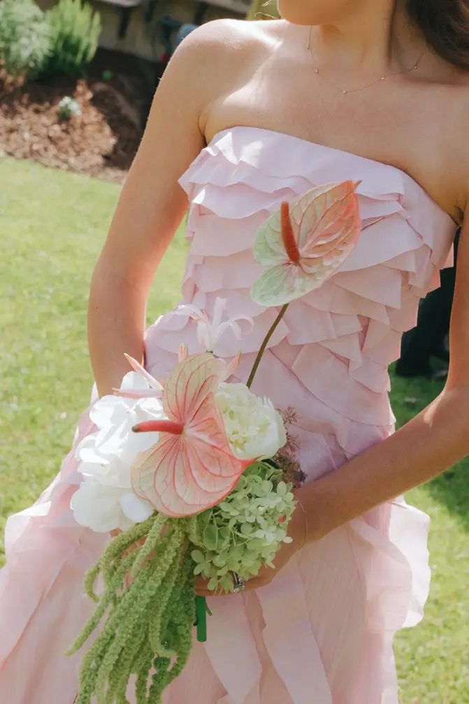 Home 6 Close-up of a modern, sculptural wedding bouquet featuring striking pink anthuriums, white blooms, and trailing green amaranthus. Bespoke floral design for a destination wedding in Portugal.